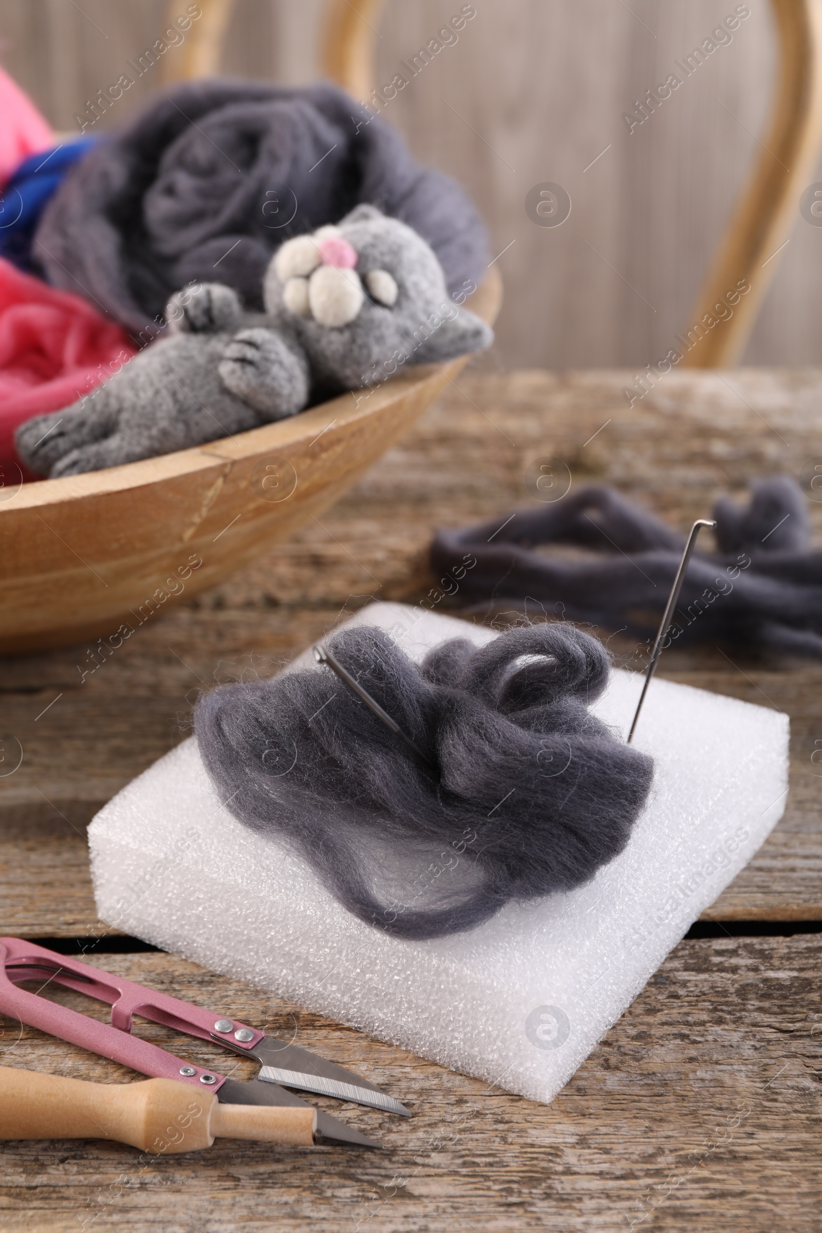 Photo of Felting tools, wool and toy cat on wooden table