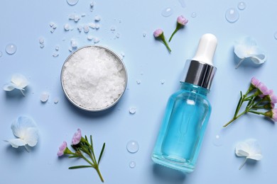 Bottle of cosmetic serum, beautiful flowers and sea salt on light blue background, flat lay