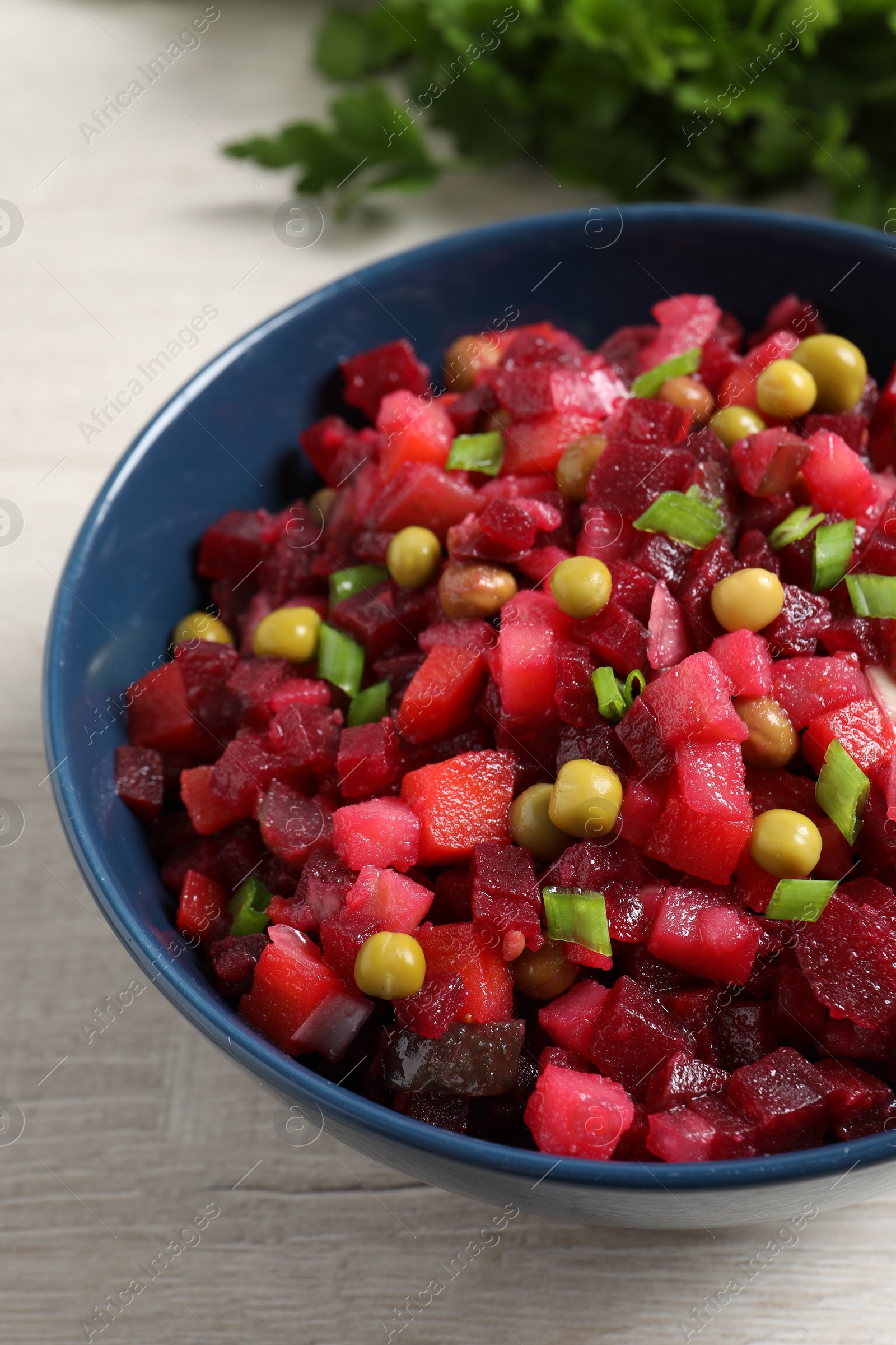 Photo of Bowl of delicious fresh vinaigrette salad on light wooden table, closeup