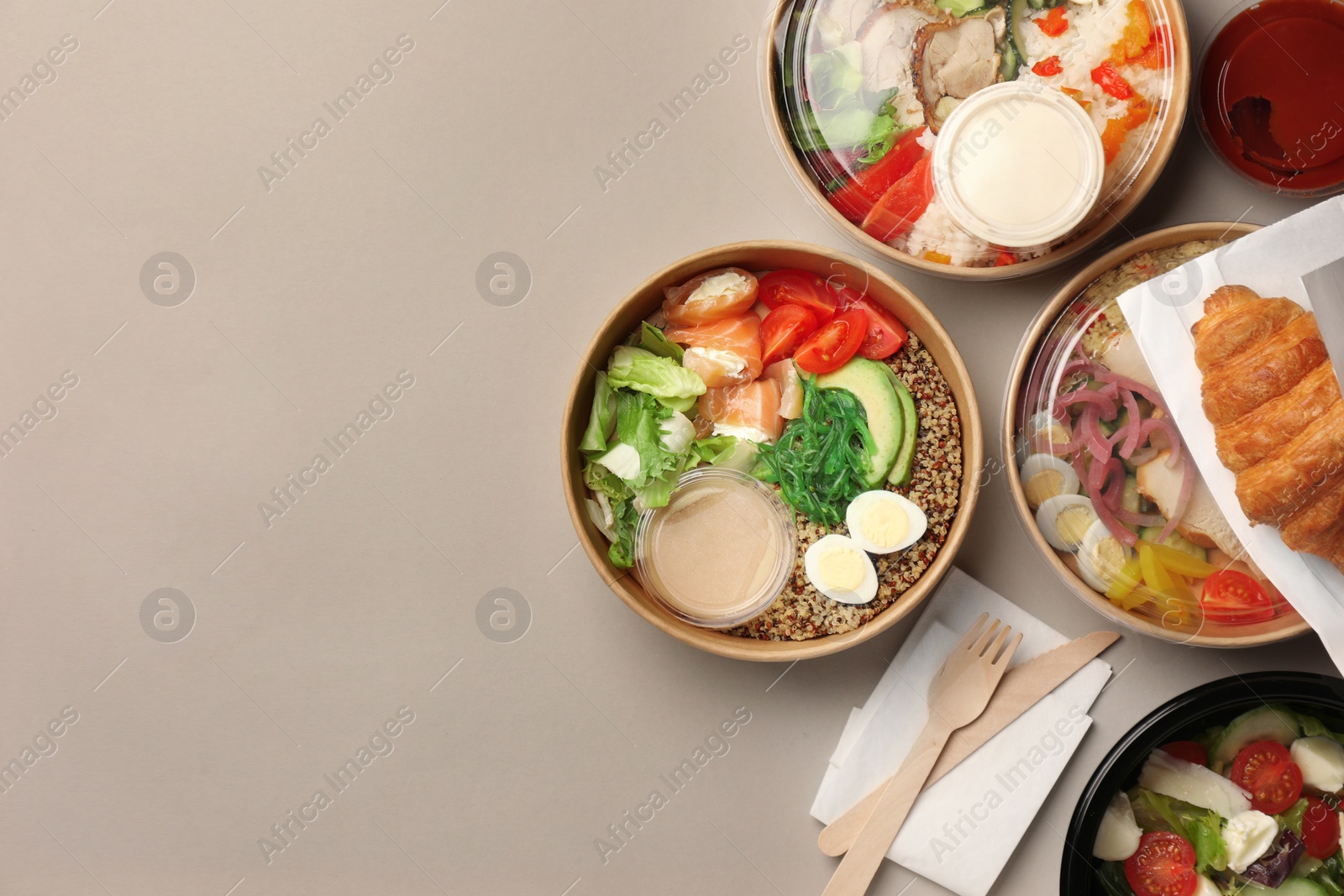 Photo of Tasty food in containers with wooden knife and fork on light grey table, flat lay. Space for text