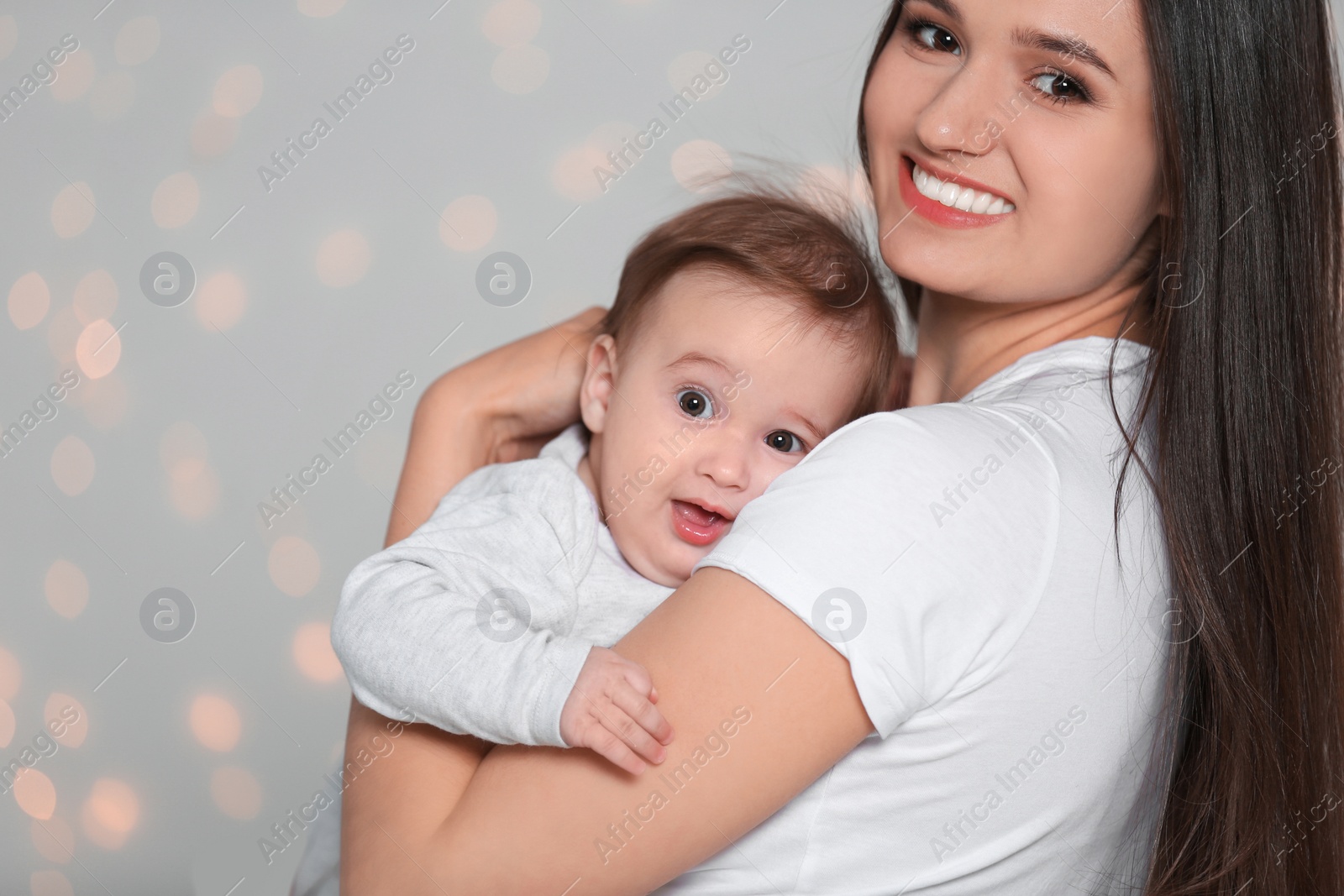 Photo of Portrait of young mother and her adorable baby against defocused lights