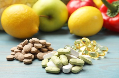 Photo of Dietary supplements. Piles of different pills near food products on light blue wooden table, closeup