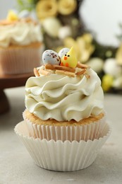 Photo of Tasty Easter cupcake with vanilla cream on gray table