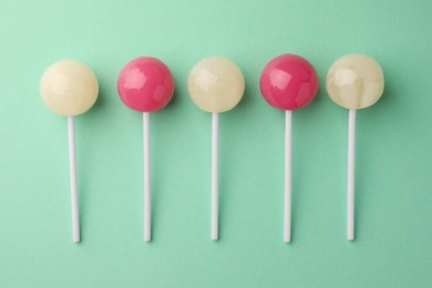 Tasty lollipops on turquoise background, flat lay