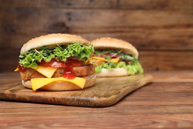 Photo of Delicious burgers with tofu, fresh vegetables and sauce on wooden table, space for text