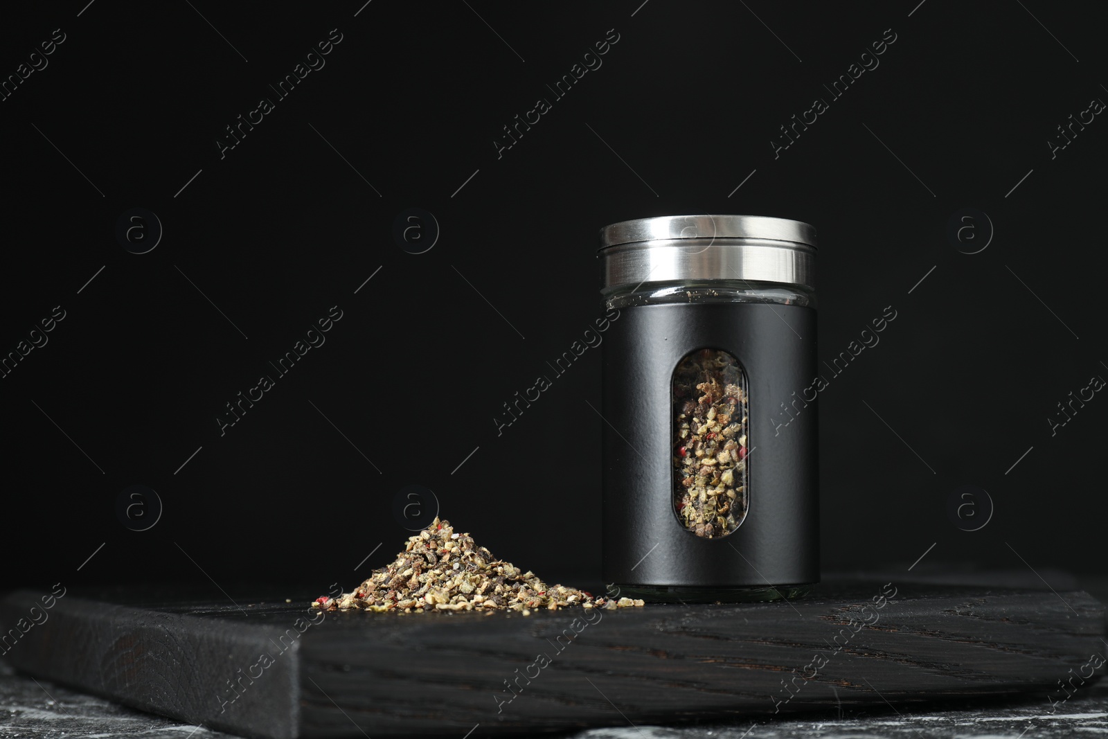 Photo of Stylish shaker with pepper on table against black background. Space for text