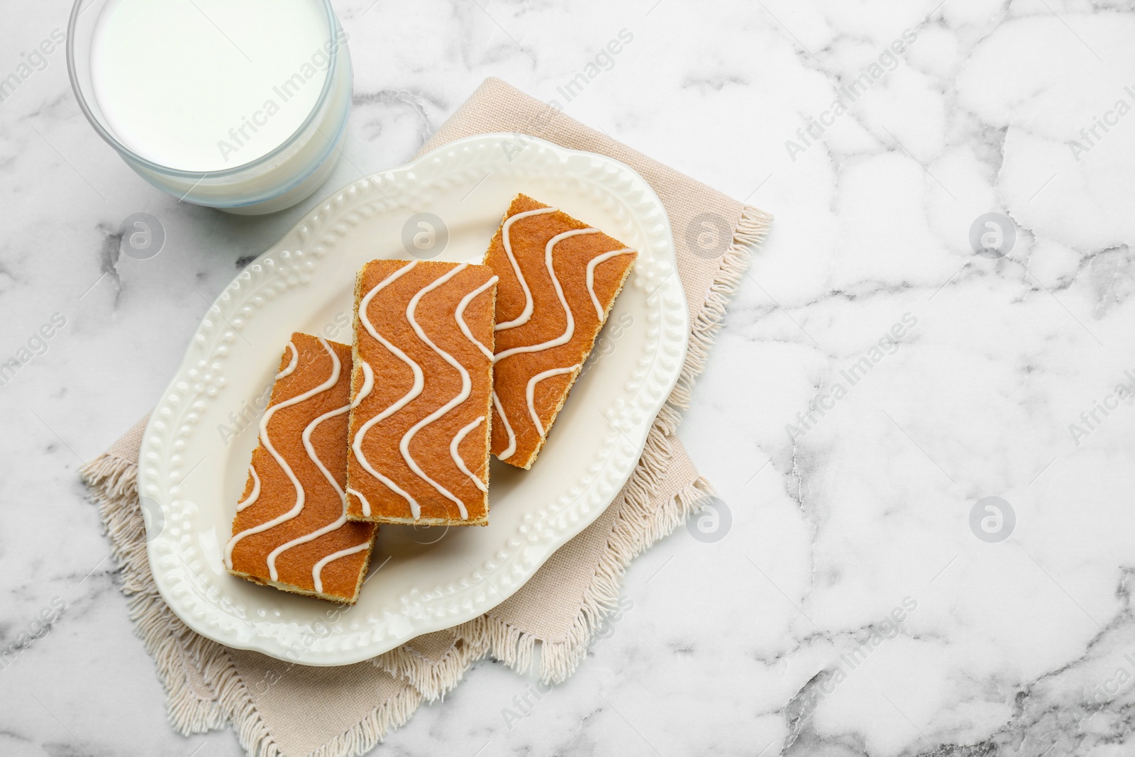 Photo of Tasty sponge cakes and milk on white marble table, flat lay. Space for text