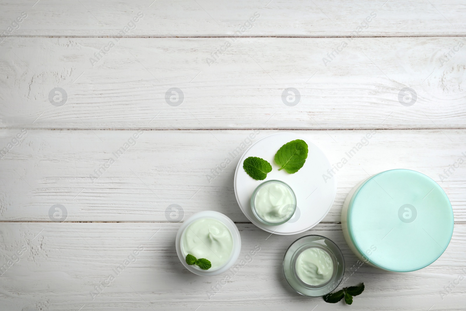 Photo of Composition with body cream in jars on wooden background, top view