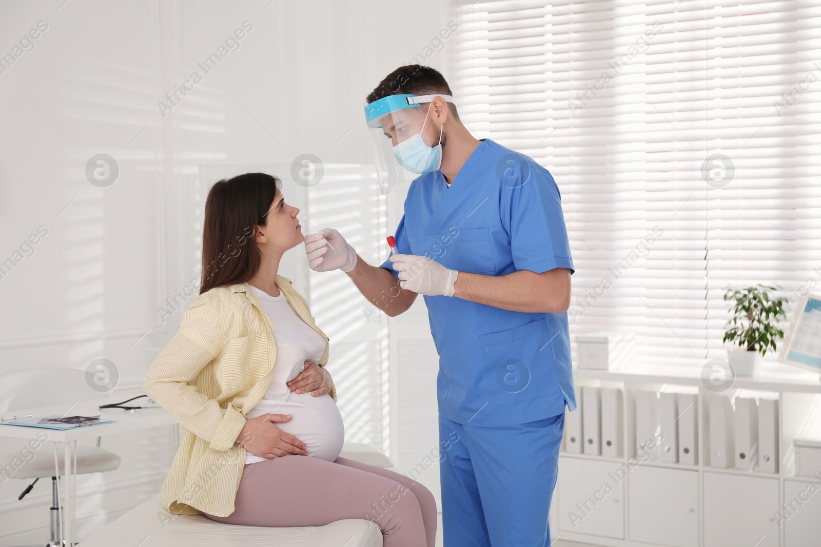 Photo of Doctor taking nasal smear of pregnant woman for coronavirus test in clinic