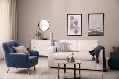 Stylish living room interior with white sofa, armchair and small coffee table