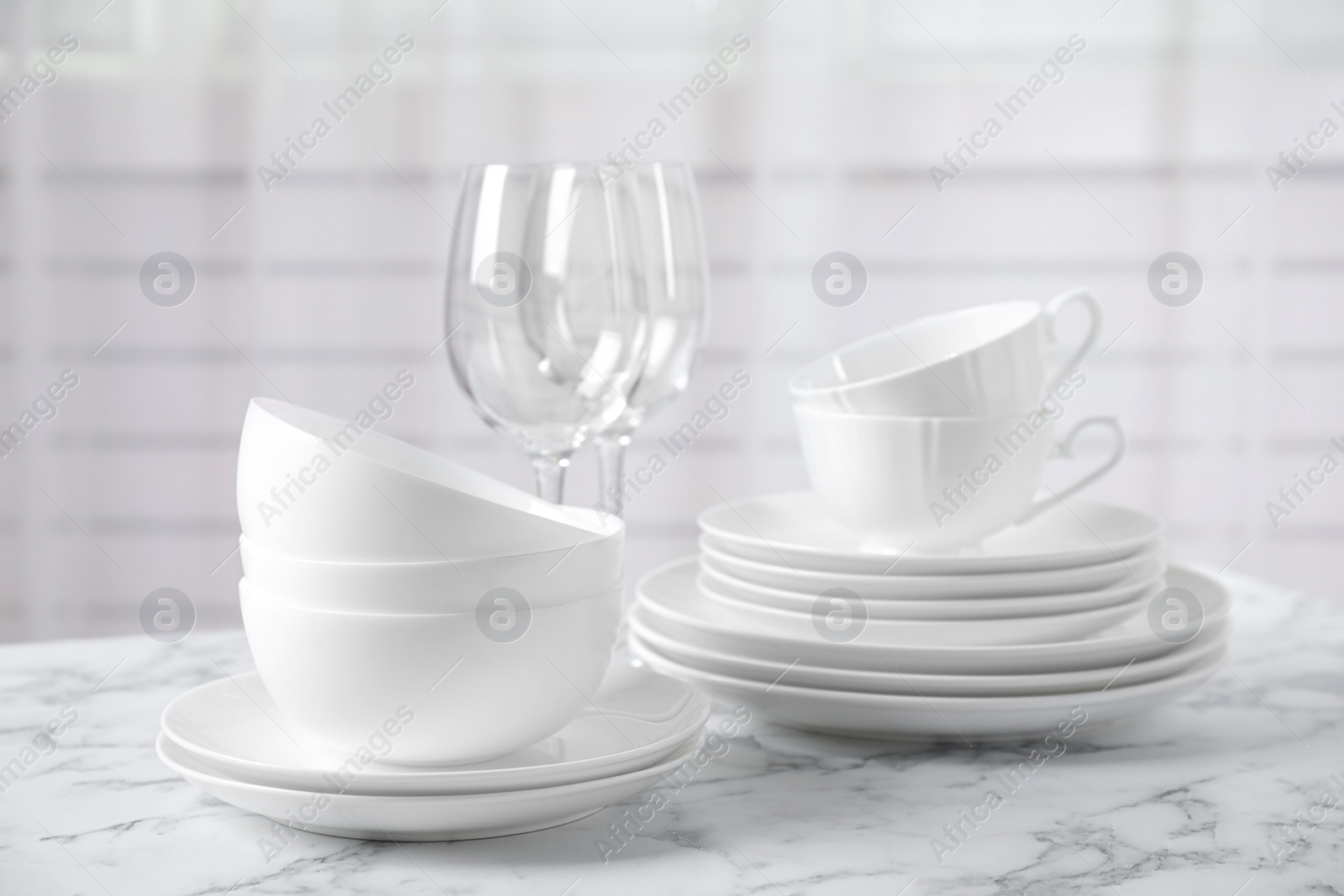 Photo of Set of clean tableware on white marble table