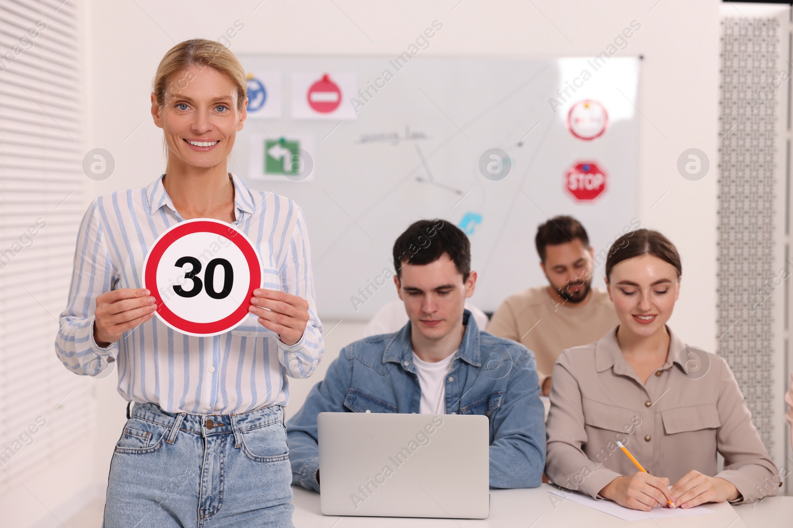 Photo of Teacher showing Speed Limit road sign during lesson in driving school