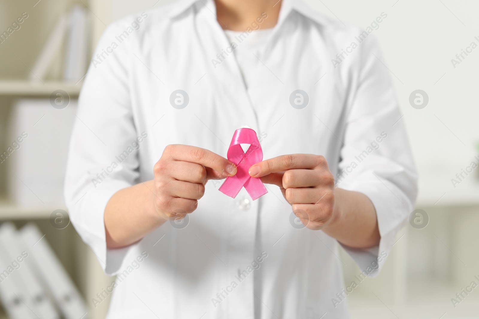 Photo of Mammologist with pink ribbon in hospital, closeup. Breast cancer awareness