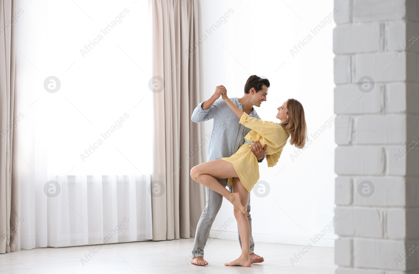 Photo of Beautiful young couple dancing in room at home