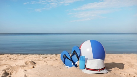 Beach accessories on sand near sea. Space for text