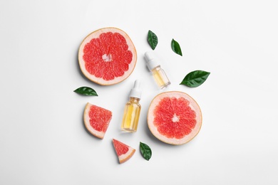 Photo of Composition with grapefruit slices and bottles of essential oil on white background, top view