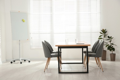 Conference room interior with wooden table and flipchart