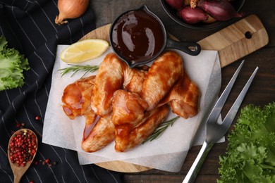 Flat lay composition with marinade, raw chicken wings and other products on wooden table