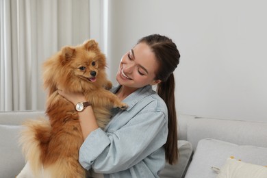 Happy young woman with cute dog at home