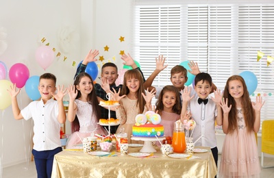 Happy children at birthday party in decorated room