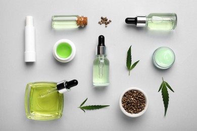 Photo of Different hemp cosmetics, green leaves and seeds on white background, flat lay