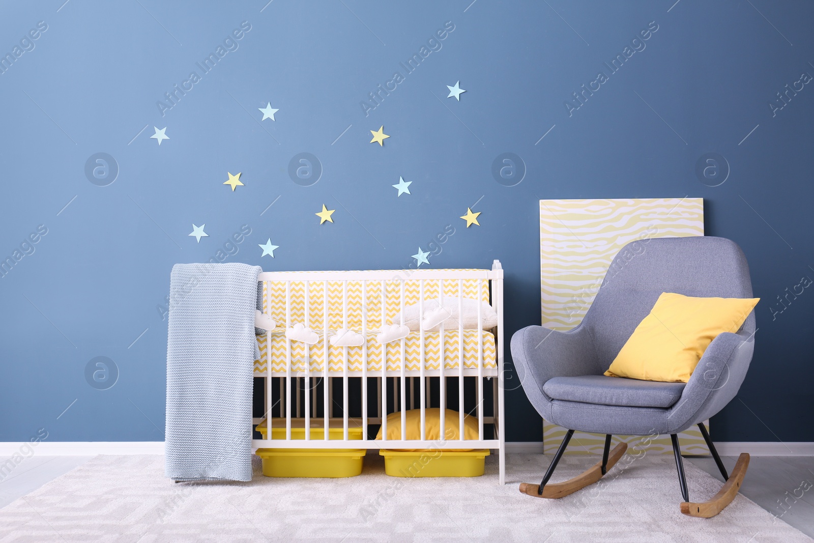 Photo of Baby room interior with crib and rocking chair near wall