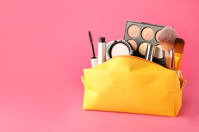 Photo of Cosmetic bag with makeup products and accessories on pink background. Space for text