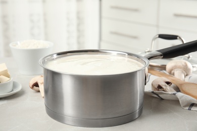Photo of Delicious creamy sauce in pan on marble table