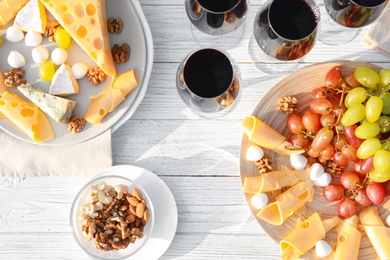 Flat lay composition with red wine and snacks on white wooden table