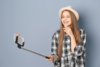 Young beautiful woman taking selfie against grey background