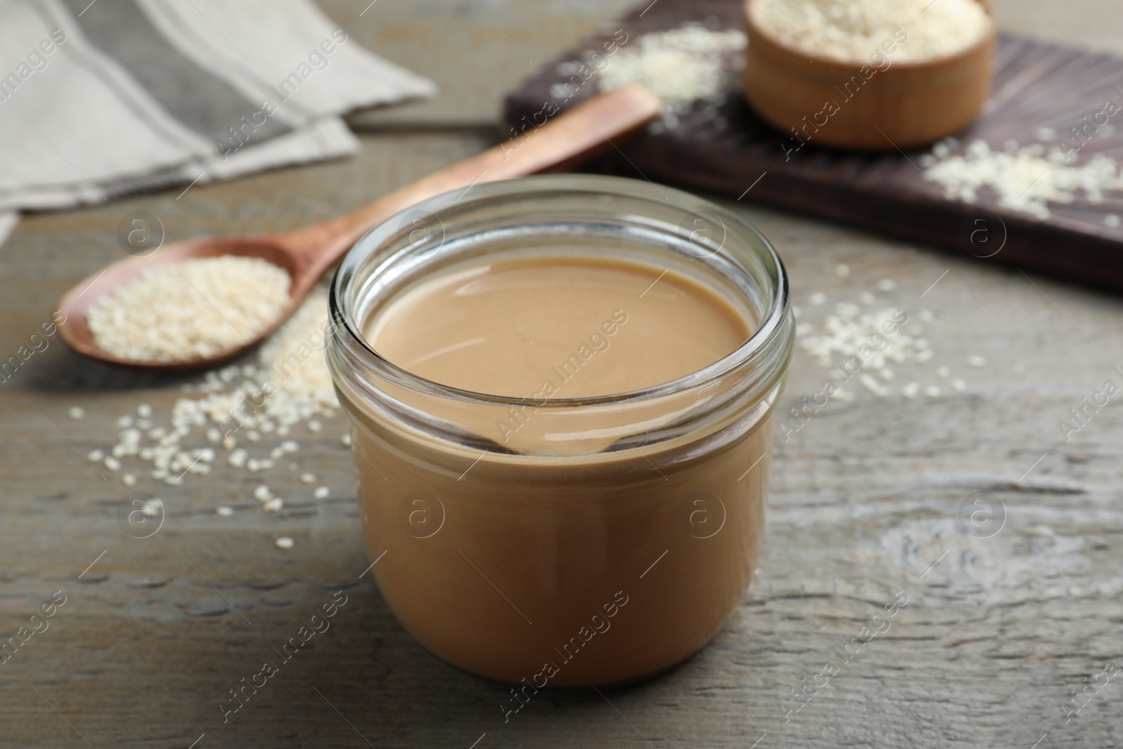 Photo of Jar of tasty sesame paste on wooden table