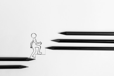 Photo of Human figure walking up drawn stairs and pencils on white background, top view