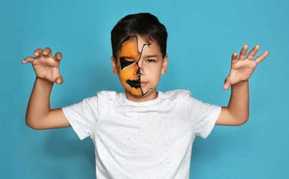 Photo of Cute little boy with face painting on blue background