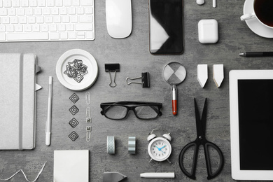 Flat lay composition with digital devices and different office items on grey stone background. Designer's workplace