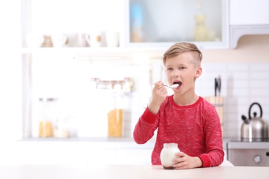 Little boy with yogurt in kitchen