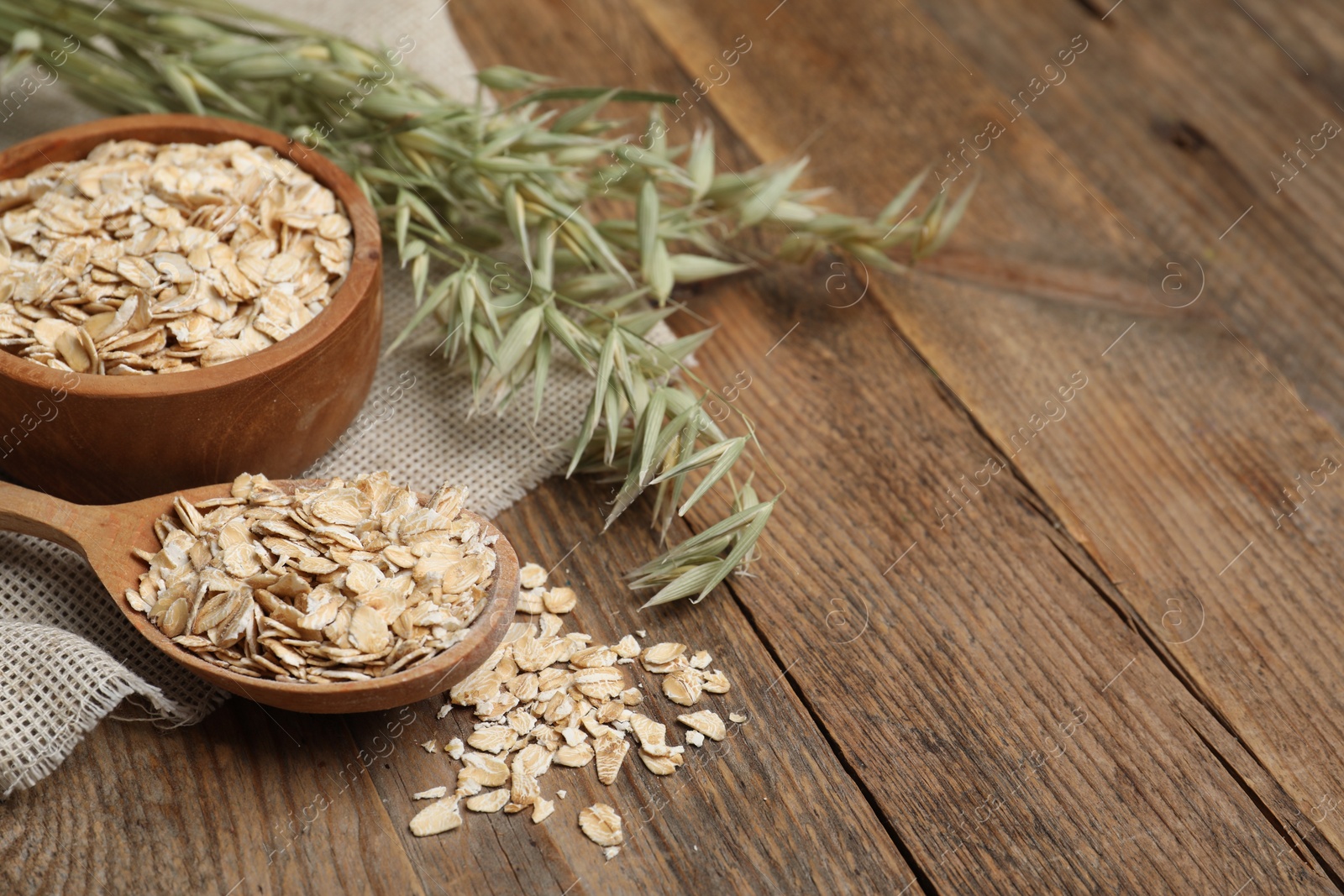 Photo of Oatmeal and branches with florets on wooden table, closeup. Space for text