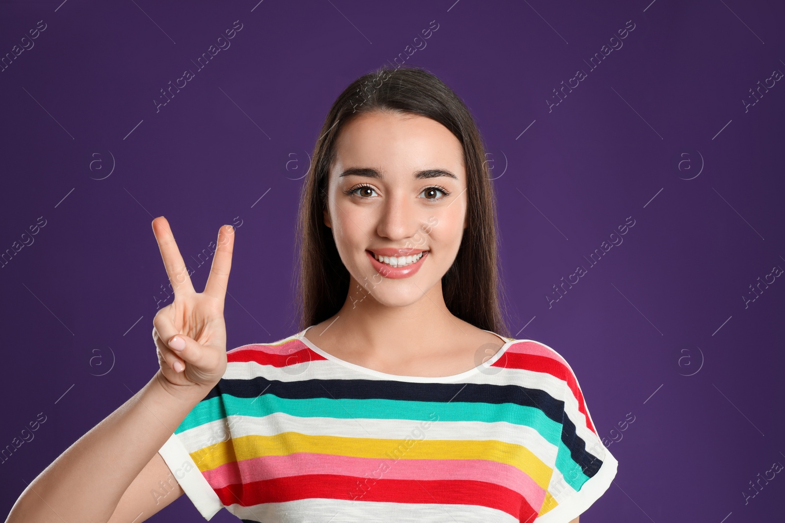 Photo of Woman showing number two with her hand on purple background