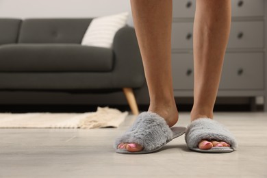 Woman wearing grey soft slippers at home, closeup
