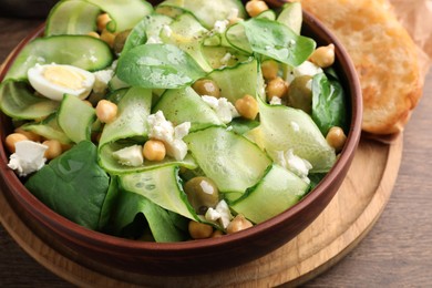 Bowl of delicious cucumber salad and toasted bread on wooden table, closeup