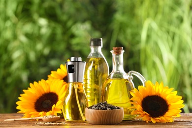 Many different bottles with cooking oil, sunflower seeds and flowers on wooden table against blurred background