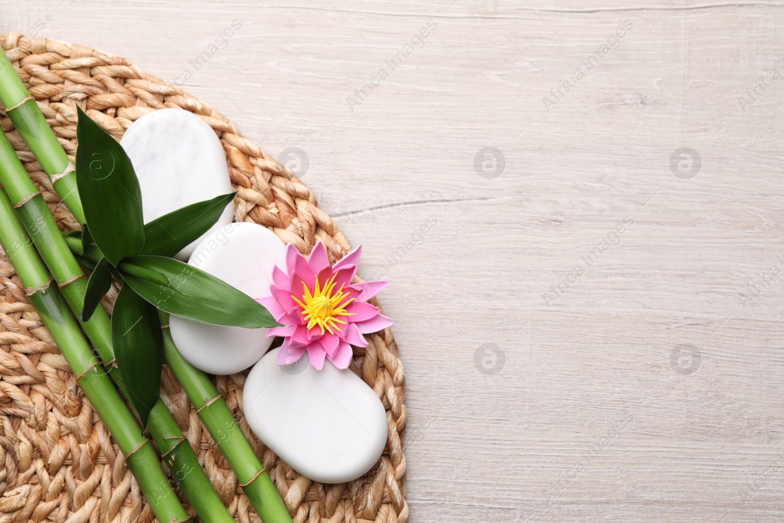 Photo of Bamboo, spa stones and flower on light wooden table, flat lay. Space for text