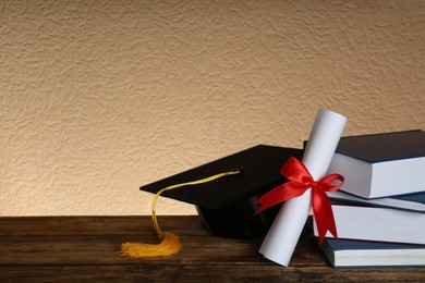 Photo of Graduation hat, books and diploma on wooden table. Space for text