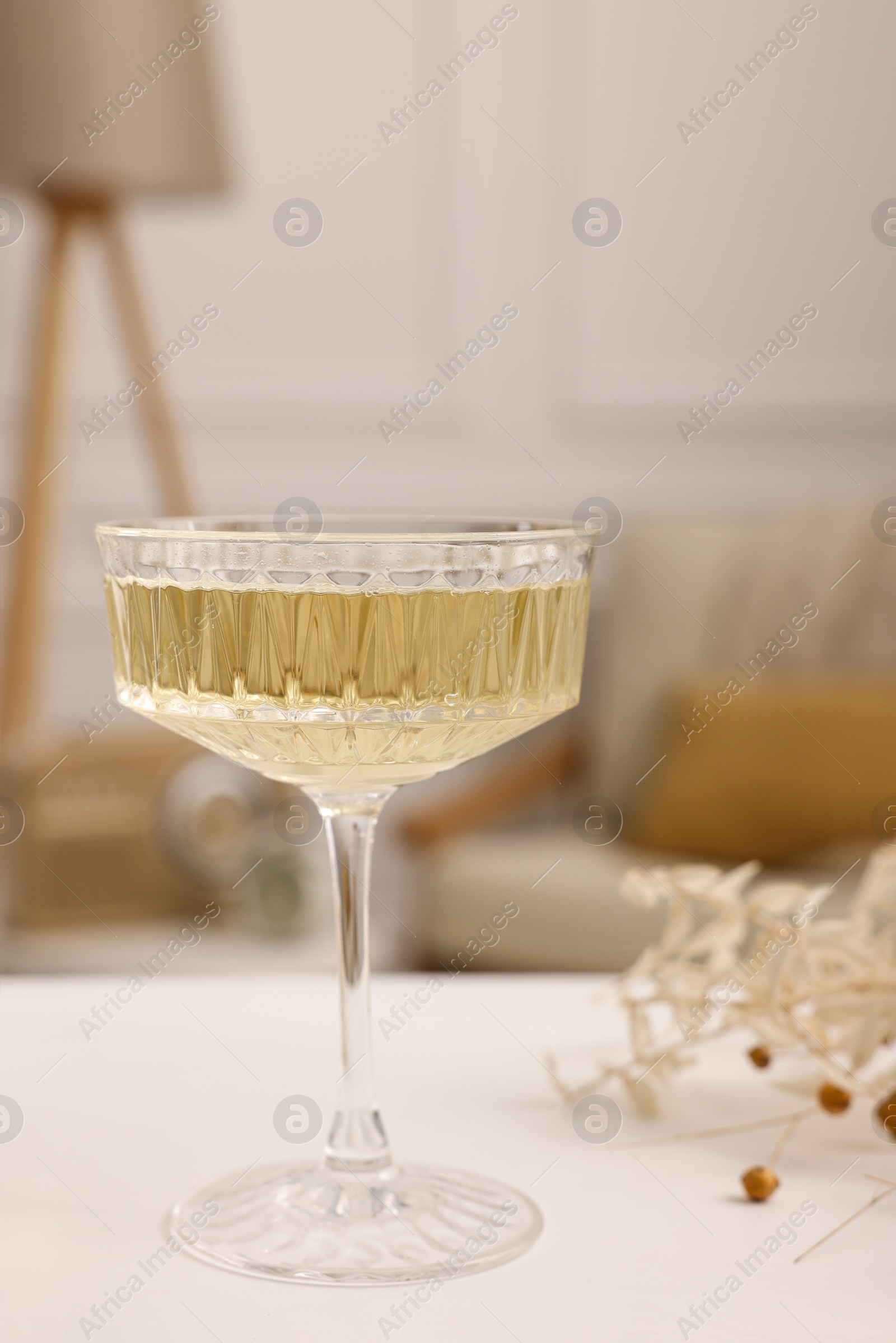 Photo of Glass of alcohol drink on table in room, closeup. Relax at home