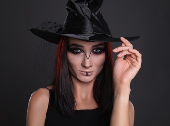 Photo of Mysterious witch wearing hat on black background