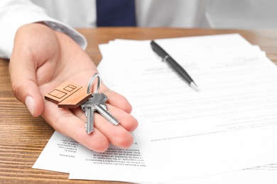Photo of Real estate agent with keys and documents at table