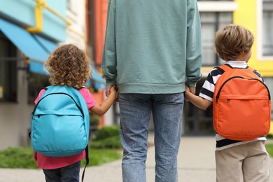 Woman and her children on their way to kindergarten outdoors, back view