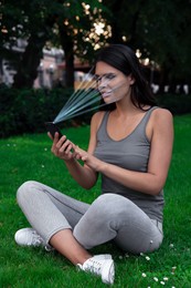 Image of Woman using smartphone with facial recognition system outdoors. Security application scanning her face for approving owner's identity