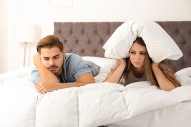 Upset young couple with relationship problems in bedroom