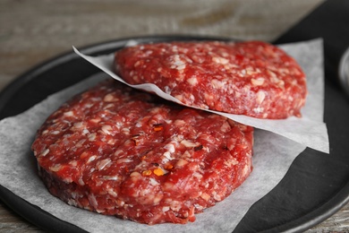 Photo of Raw meat cutlets for burger on wooden table, closeup