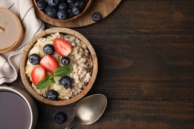 Photo of Tasty oatmeal with strawberries, blueberries and almond petals served on wooden table, flat lay. Space for text